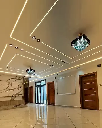 Parlak zeminli geniş salon, çizgi şeklinde tavan aydınlatması, kristal avize ve ahşap kapılar